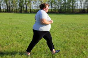 Overweight woman running on meadow